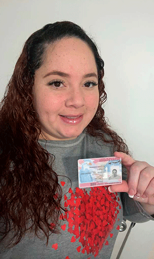 “Mujer inmigrante sonriendo mientras sostiene su tarjeta de permiso de trabajo de inmigración